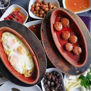 Top view of a traditional Turkish breakfast featuring eggs, meatballs, and assorted meze dishes.
